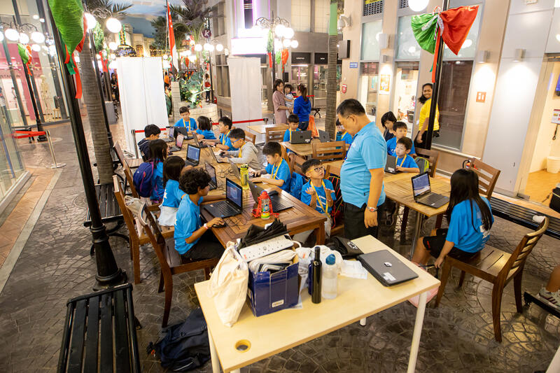 Kids coding at tables during CodeFest hackathon event
