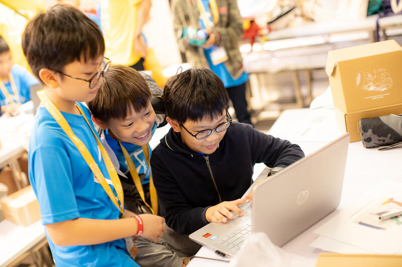 Kids sharing a laptop and collaborating at CodeFest