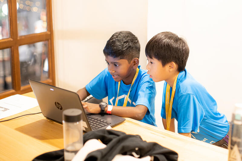 Two kids coding together on a laptop at CodeFest