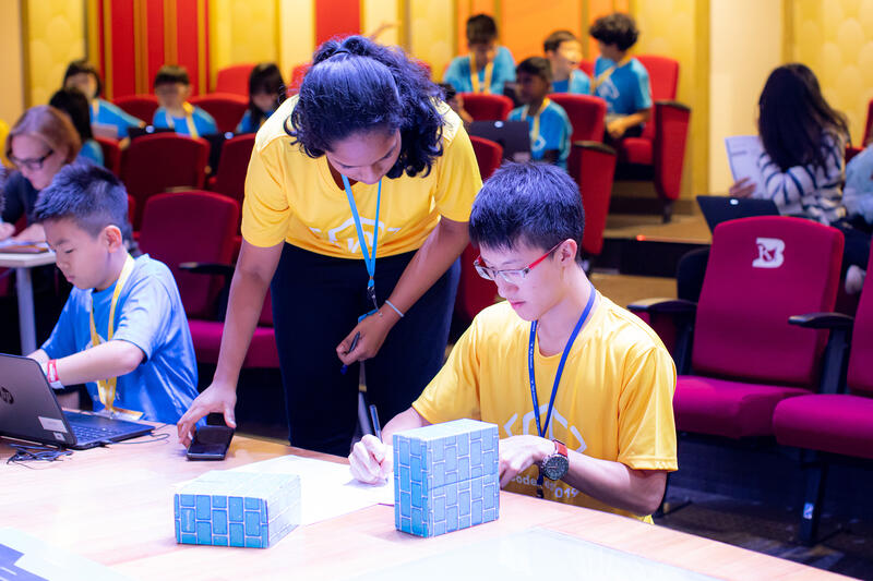Volunteer helping student with coding project at CodeFest