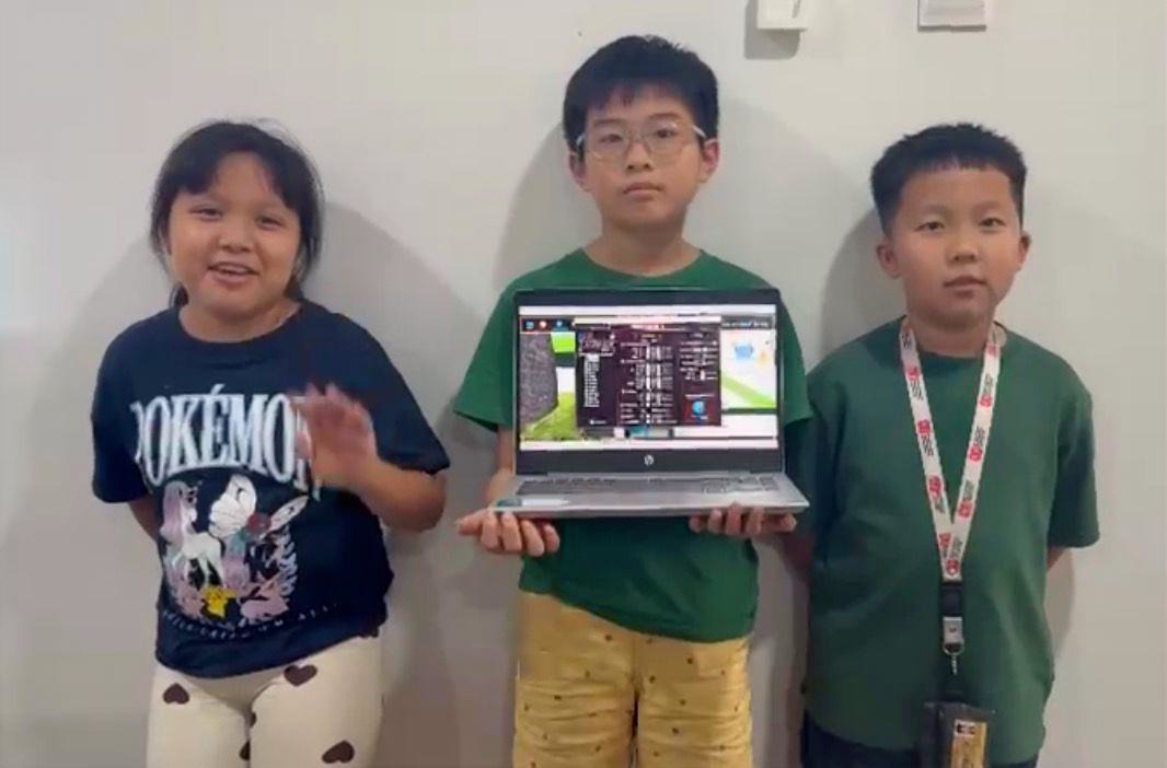 Three kids holding laptop showing CoSpace Rescue project