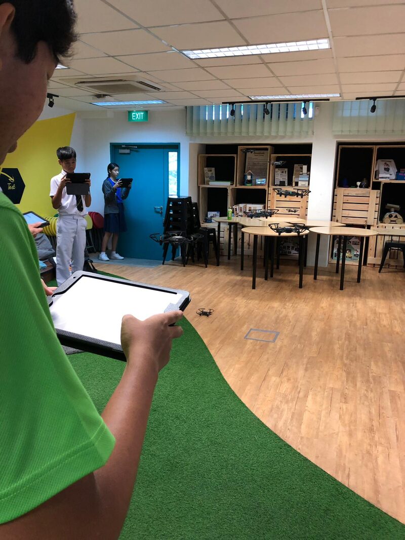 Students programming drones with tablets at school